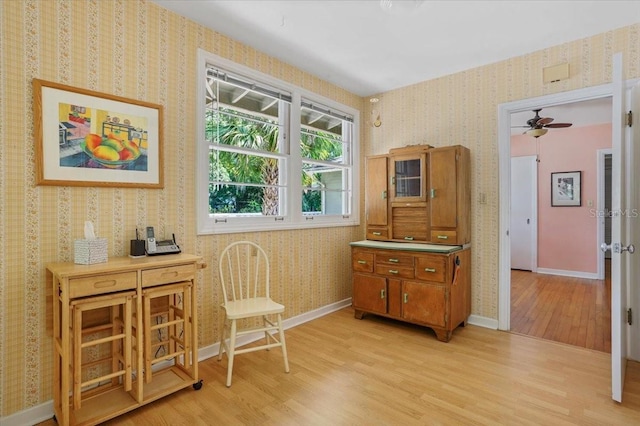 sitting room featuring wallpapered walls, ceiling fan, baseboards, and light wood-type flooring