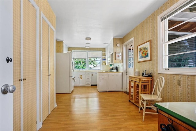 interior space featuring white appliances, light wood-style floors, wallpapered walls, light countertops, and white cabinetry