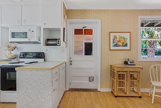 kitchen with white cabinets, white microwave, range with electric stovetop, and light wood-style flooring