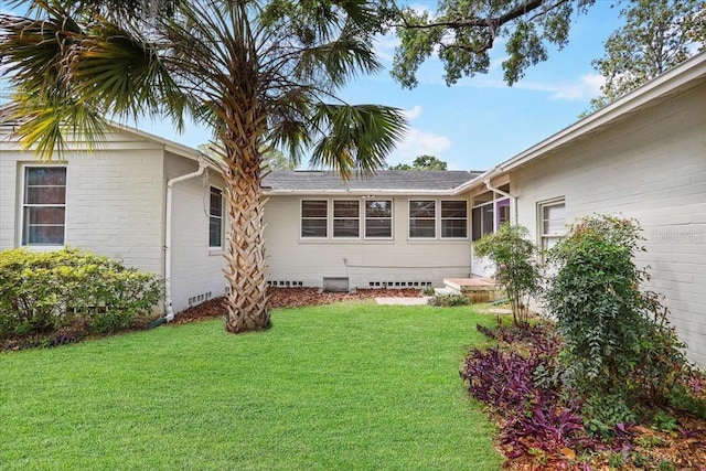 rear view of house featuring a yard and crawl space