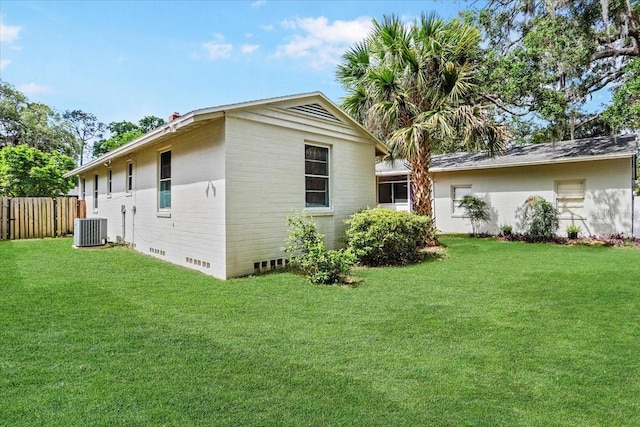 view of property exterior with a lawn, central AC unit, and fence