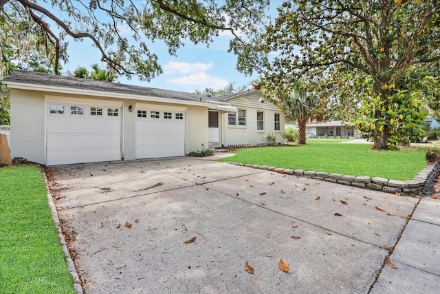 ranch-style house featuring an attached garage, concrete driveway, and a front yard