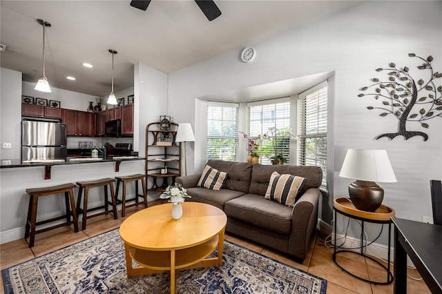 living room featuring baseboards, ceiling fan, light tile patterned flooring, and vaulted ceiling