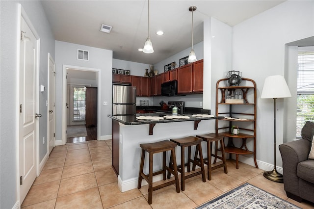 kitchen featuring visible vents, freestanding refrigerator, electric range, black microwave, and dark countertops