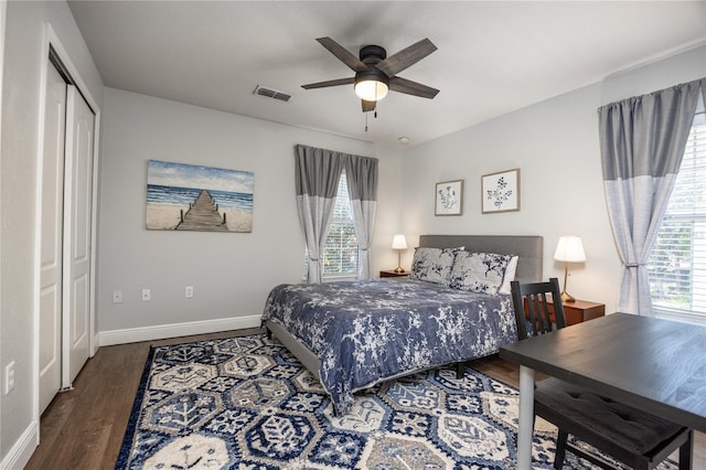 bedroom with a ceiling fan, baseboards, wood finished floors, visible vents, and a closet