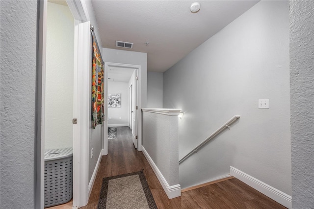 hall featuring baseboards, wood finished floors, and an upstairs landing