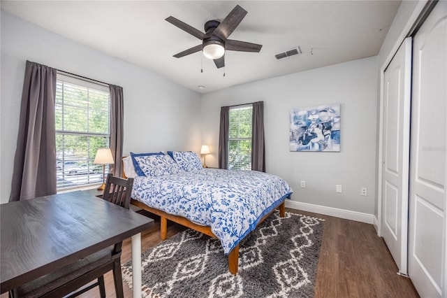 bedroom featuring visible vents, baseboards, wood finished floors, and multiple windows