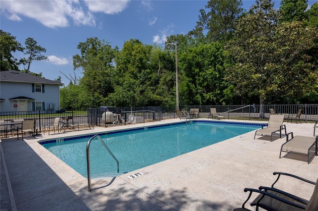 community pool with fence and a patio area