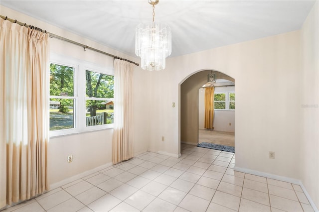 5620 NW 25th St, Gainesville, FL 32653 - spare room featuring a chandelier, baseboards, light tile patterned flooring, and arched walkways