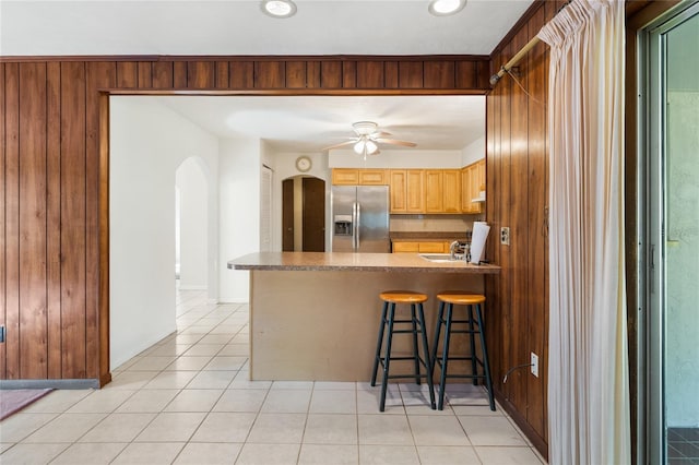 5620 NW 25th St, Gainesville, FL 32653 - kitchen featuring ceiling fan, a kitchen bar, stainless steel fridge, arched walkways, and light tile patterned floors