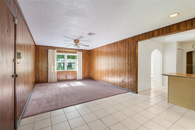 5620 NW 25th St, Gainesville, FL 32653 - empty room featuring a ceiling fan, visible vents, wood walls, arched walkways, and light colored carpet