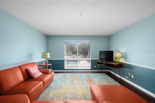 living room featuring a textured ceiling, baseboards, and wood finished floors