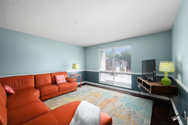living area with baseboards, a textured ceiling, and wood finished floors