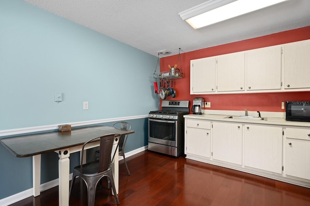 kitchen featuring a sink, stainless steel range with gas stovetop, dark wood-style flooring, black microwave, and light countertops