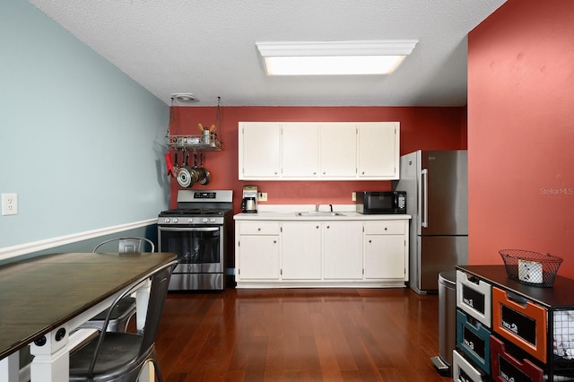 kitchen with white cabinets, stainless steel appliances, dark wood-style flooring, and a sink