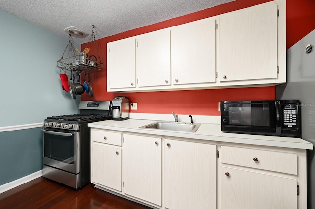 kitchen with stainless steel gas range, black microwave, a sink, and light countertops