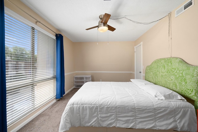 carpeted bedroom with visible vents, baseboards, and a ceiling fan