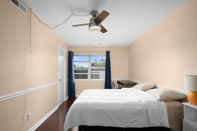 bedroom featuring a textured ceiling, visible vents, dark wood-style flooring, baseboards, and ceiling fan