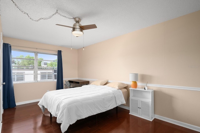 bedroom featuring a textured ceiling, baseboards, and wood finished floors