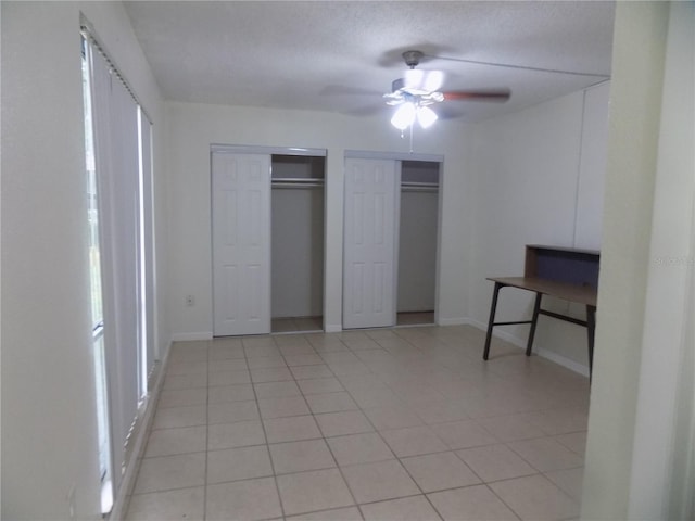 2811 SW Archer Rd Unit W 191, Gainesville, FL 32608 - unfurnished bedroom featuring multiple closets, light tile patterned floors, baseboards, and a ceiling fan