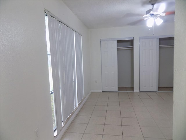 2811 SW Archer Rd Unit W 191, Gainesville, FL 32608 - unfurnished bedroom featuring light tile patterned floors, baseboards, multiple closets, and ceiling fan