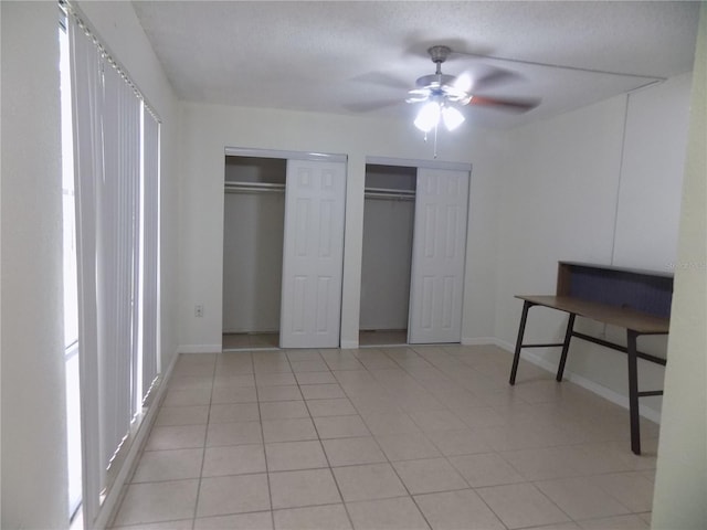 2811 SW Archer Rd Unit W 191, Gainesville, FL 32608 - unfurnished bedroom featuring two closets, baseboards, light tile patterned floors, and a ceiling fan