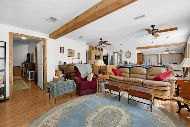 living area with a ceiling fan, visible vents, and wood finished floors