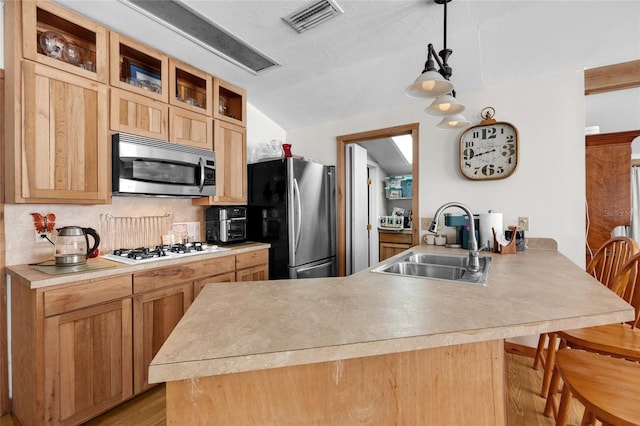 kitchen with visible vents, a peninsula, glass insert cabinets, a sink, and stainless steel appliances