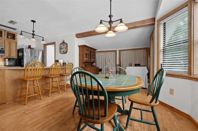 dining room featuring visible vents, baseboards, a chandelier, vaulted ceiling with beams, and light wood-style flooring