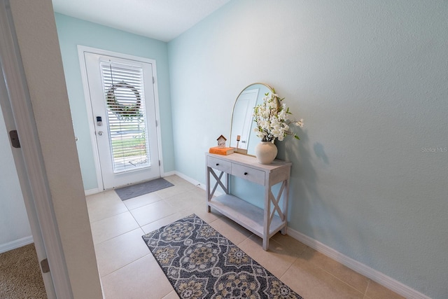 doorway to outside with baseboards and light tile patterned floors