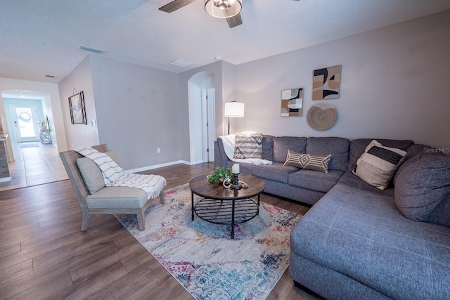 living room with arched walkways, ceiling fan, wood finished floors, and visible vents