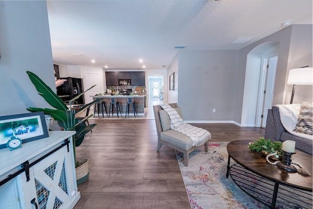 living room with dark wood finished floors, visible vents, baseboards, arched walkways, and recessed lighting