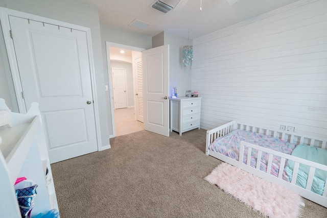 bedroom featuring a nursery area, visible vents, and light carpet