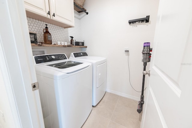 laundry room with washing machine and clothes dryer, baseboards, light tile patterned floors, and cabinet space