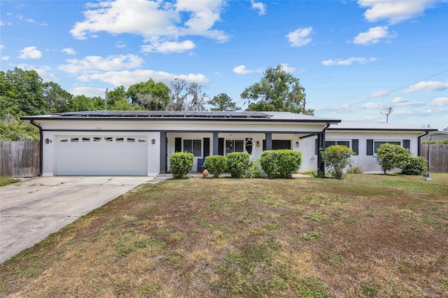 ranch-style home with fence, solar panels, a garage, concrete driveway, and a front lawn