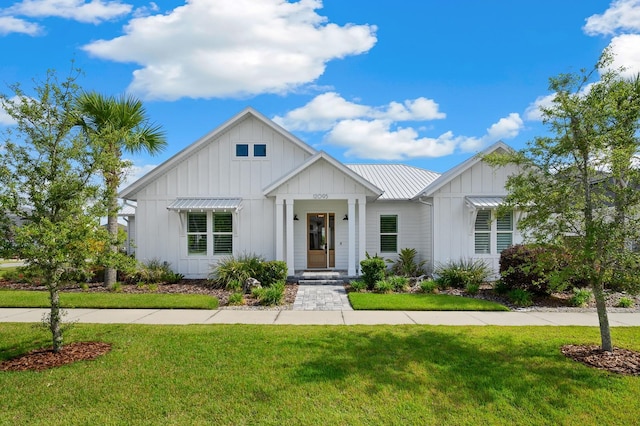 modern inspired farmhouse featuring board and batten siding, a front yard, and metal roof