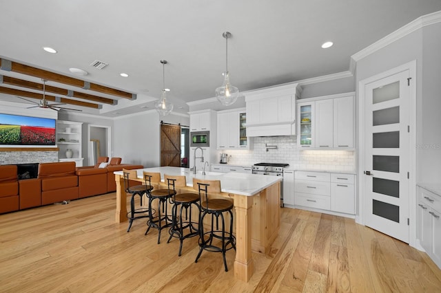 kitchen with light wood-style floors, recessed lighting, a kitchen breakfast bar, ornamental molding, and stainless steel appliances