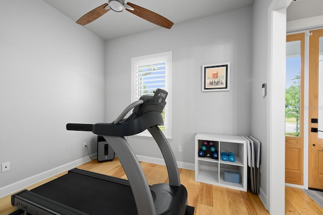 exercise room with light wood finished floors, a ceiling fan, and baseboards