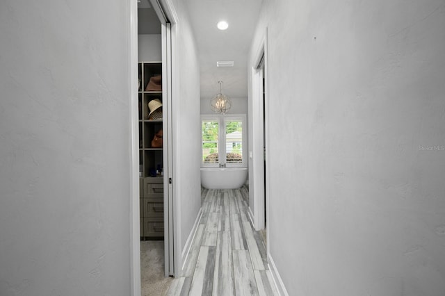 full bath featuring a freestanding tub, baseboards, wood finished floors, and a chandelier