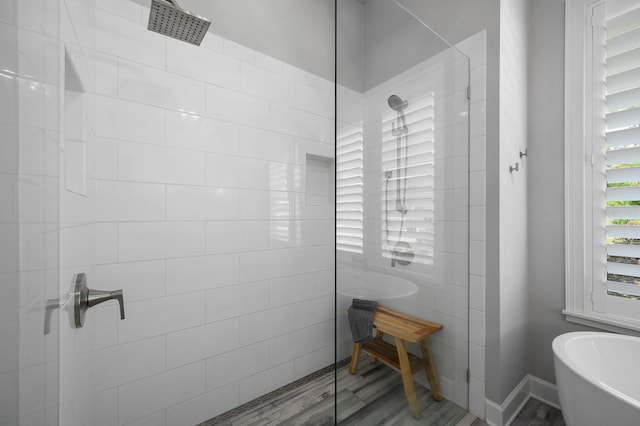 full bath featuring a walk in shower, a freestanding tub, and wood finished floors