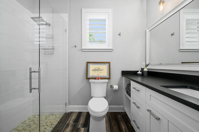 full bath featuring a stall shower, toilet, wood finished floors, vanity, and baseboards