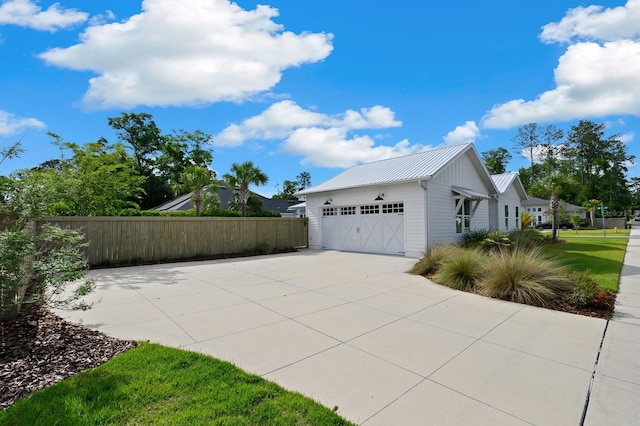 view of home's exterior with fence, metal roof, driveway, and a garage
