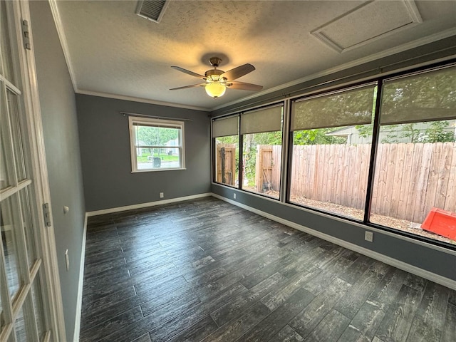 empty room with ornamental molding, attic access, visible vents, and wood finished floors