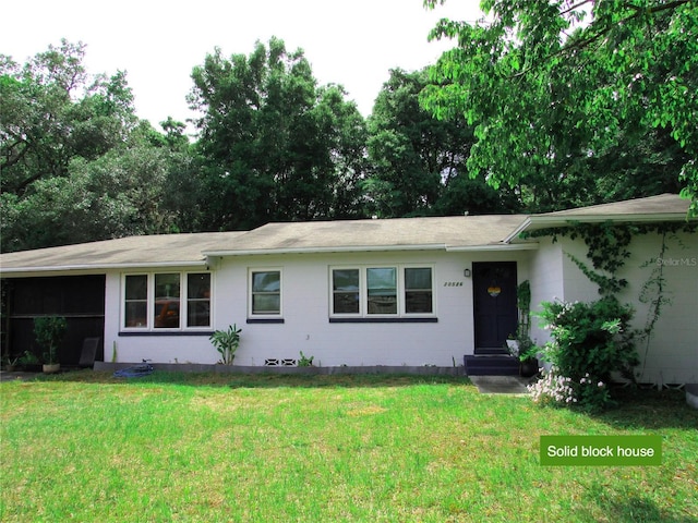 single story home with roof with shingles, a front yard, and concrete block siding