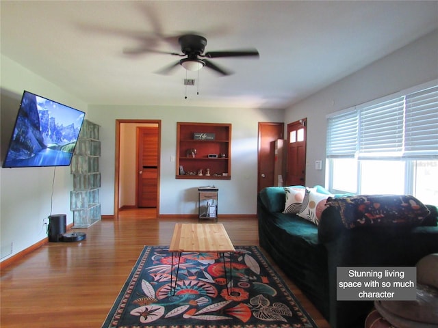 living room featuring baseboards, a ceiling fan, visible vents, and wood finished floors