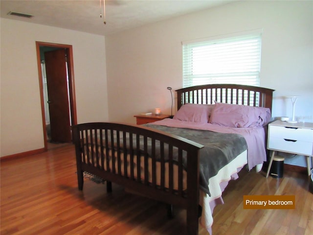 bedroom featuring baseboards, visible vents, and wood finished floors