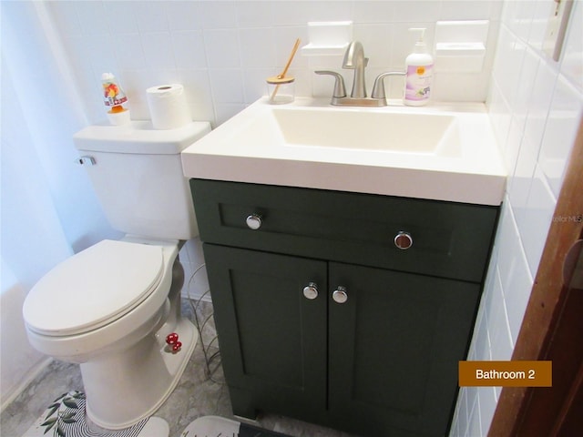 bathroom featuring backsplash, tile walls, vanity, and toilet