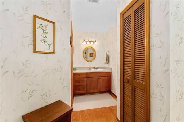 7022 NW 51st Ter, Gainesville, FL 32653 - bathroom with wood finished floors, a closet, wallpapered walls, visible vents, and vanity