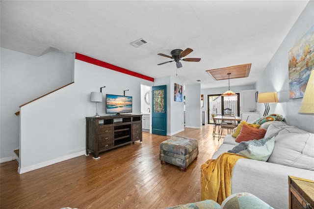 living room with wood finished floors, a ceiling fan, and baseboards