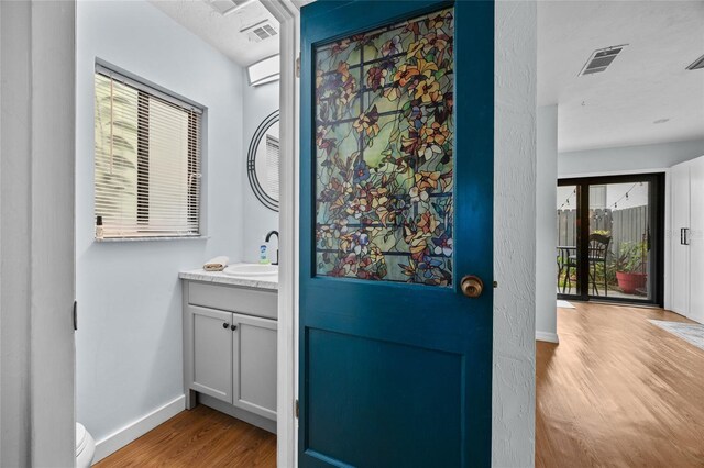 bathroom featuring wood finished floors, baseboards, vanity, and toilet